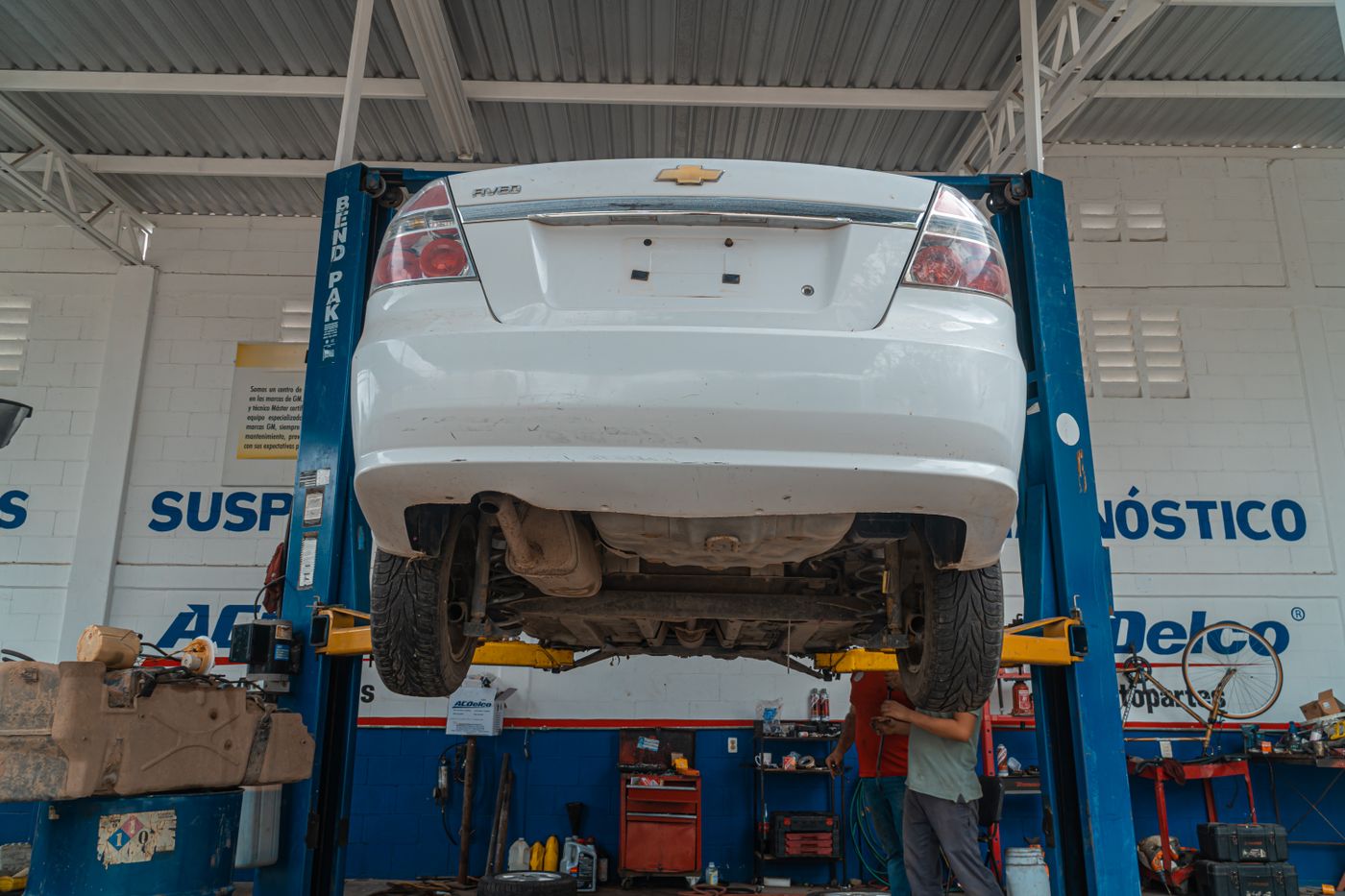 Auto blanco levantado en un taller mecánico